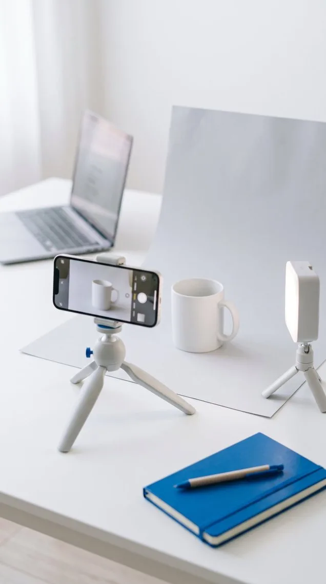 A phone on a small tripod filming a white mug for a product video